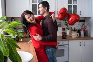 homme et femme amoureux date à la maison dans la cuisine câlins heureux. saint valentin, couple heureux, histoire d'amour. nid d'amour, logement pour jeune famille photo