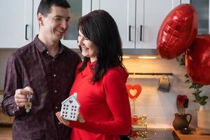 homme et femme amoureux datent à la maison dans la cuisine avec les clés de la maison. saint valentin, couple heureux, histoire d'amour. nid d'amour, hypothèque, déménagement, achat, immobilier, logement pour jeune famille photo