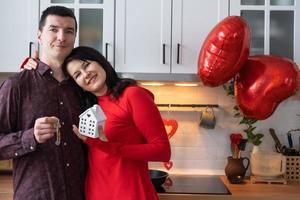 homme et femme amoureux datent à la maison dans la cuisine avec les clés de la maison. saint valentin, couple heureux, histoire d'amour. nid d'amour, hypothèque, déménagement, achat, immobilier, logement pour jeune famille photo