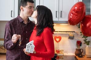 homme et femme amoureux datent à la maison dans la cuisine avec les clés de la maison. saint valentin, couple heureux, histoire d'amour. nid d'amour, hypothèque, déménagement, achat, immobilier, logement pour jeune famille photo