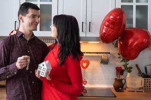 homme et femme amoureux datent à la maison dans la cuisine avec les clés de la maison. saint valentin, couple heureux, histoire d'amour. nid d'amour, hypothèque, déménagement, achat, immobilier, logement pour jeune famille photo