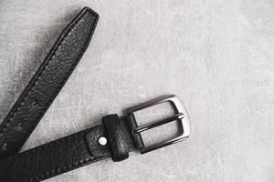 ceinture en cuir homme noir avec insigne métallique fond béton gris. photo