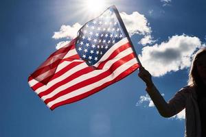 femme tient le drapeau des états-unis contre le ciel bleu photo