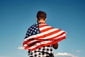 l'homme tient le drapeau national des états-unis contre le ciel bleu photo