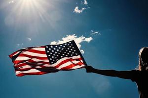 femme tient le drapeau des états-unis contre le ciel bleu photo