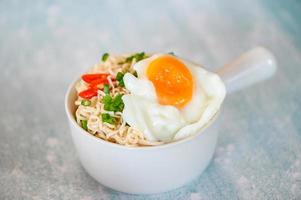 nouilles instantanées cuisine savoureuse manger avec bol, bol de nouilles avec œuf à la coque légumes oignon de printemps et piment sur la nourriture de table, soupe de nouilles photo