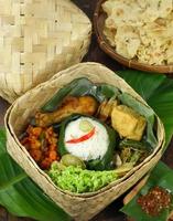 nasi besek bambu, est un aliment composé de riz et de plats d'accompagnement qui peuvent être composés de pommes de terre au chili, de poulet frit, de tofu, de sauce chili et de légumes frais et emballés dans une boîte à lunch en bambou photo