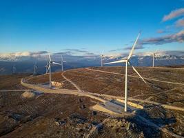 moulins à vent sur les collines au coucher du soleil. énergie renouvelable, énergie verte. montagnes en arrière-plan avec de la neige. l'énergie éolienne et respectueux de l'environnement. avenir durable. mettre fin aux énergies fossiles. photo