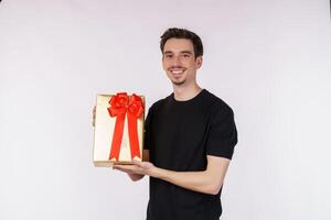 portrait d'un jeune homme caucasien heureux montrant la boîte actuelle et regardant la caméra isolée sur fond blanc. notion de fête d'anniversaire. photo