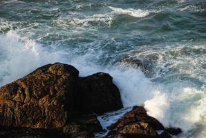 vagues frappant les rochers au coucher du soleil photo