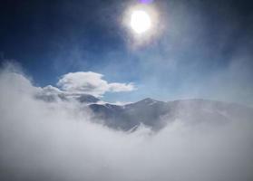 vue du soleil depuis le sommet de la montagne à travers le brouillard neigeux photo