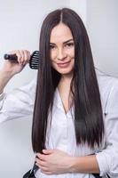 jeune femme peignant ses longs cheveux noirs avec un peigne dans un salon de beauté photo
