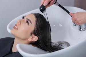 coiffeur professionnel laver les cheveux de la jeune femme dans un salon de beauté. gros plan des cheveux de la femme dans un salon de beauté, concept de coiffure photo