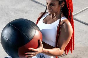fermer. femme athlétique faisant de l'exercice avec med ball. force et motivation.photo d'une femme sportive en vêtements de sport à la mode photo