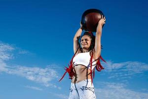 ciel de fond. femme athlétique avec ballon médical. force et motivation.photo d'une femme sportive en vêtements de sport à la mode photo