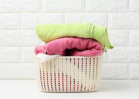 nettoyer les serviettes éponge roulées dans un panier en plastique sur une étagère blanche, intérieur de la salle de bain photo