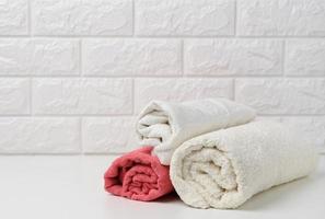 serviettes éponge roulées blanches propres sur une étagère blanche, intérieur de la baignoire photo