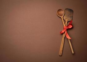 vieille cuillère et spatule attachées avec un ruban rouge sur fond marron photo