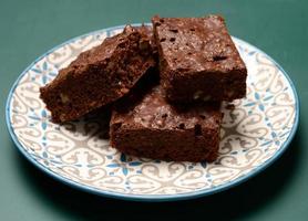 des morceaux carrés de gâteau au chocolat et aux noix de brownie se trouvent dans une assiette ronde photo