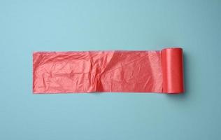 rouleau de sacs en plastique transparent rouge pour poubelle sur fond bleu photo