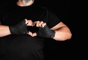 l'athlète montre le symbole du coeur, la paume d'un homme est enveloppée dans un bandage de sport noir photo