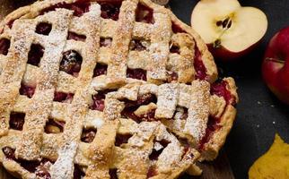 tarte aux pommes traditionnelle ronde cuite au four sur planche de bois marron et pommes rouges fraîches, vue de dessus photo