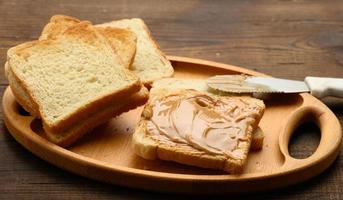 beurre d'arachide sur une tranche carrée de farine de blé blanc, petit-déjeuner photo