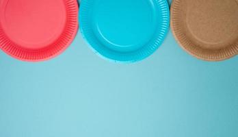 assiettes jetables en papier vides sur fond bleu, vue de dessus. photo