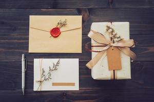 Au-dessus de la boîte cadeau artisanale et carte de vœux avec stylo sur fond de table en bois photo