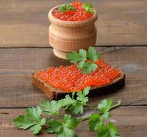 le caviar de saumon rouge repose sur un morceau de pain de seigle. table en bois marron photo