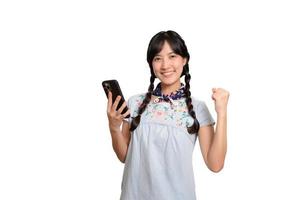 portrait d'heureuse belle jeune femme asiatique en robe denim à l'aide d'un smartphone sur fond blanc. tourné en studio photo