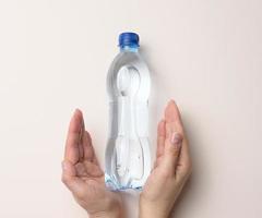 Plastique transparent bouteille avec en buvant l'eau sur une beige Contexte photo