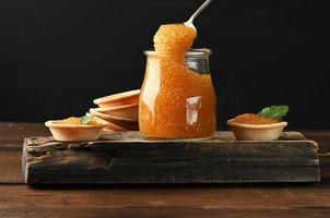 caviar de brochet dans un bocal en verre et tartelettes rondes sur fond noir photo