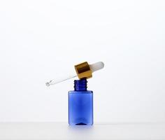 flacon en verre bleu avec une pipette sur fond blanc. modèle pour les produits cosmétiques liquides, la publicité et la promotion photo