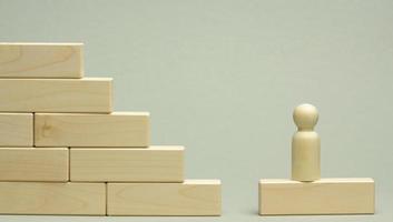 en bois figurine de une homme des stands sur une escalier fabriqué de blocs sur le premier étape photo