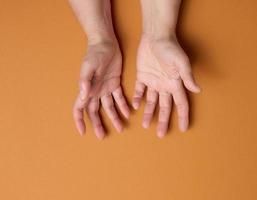 deux mains féminines sur fond marron. paumes vides ouvertes, vue de dessus photo