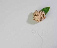 froissé feuille de marron papier et une vert feuille sur une gris arrière-plan, forme de une lumière ampoule photo