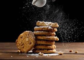 empiler de cuit rond biscuits saupoudré avec en poudre sucre sur une en bois tableau, noir Contexte photo