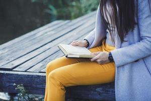 femme est assis bois pont et détient une livre photo