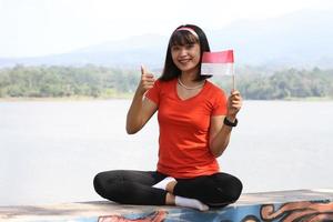 belle jeune femme asiatique portant le drapeau indonésien avec un visage joyeux photo