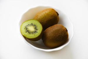 kiwis frais et juteux, hachés et entiers sur une assiette blanche. délicieux fruits et morceaux de kiwi vert. photo