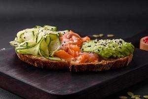 délicieux marron pain pain grillé avec saumon, avocat, concombre et sésame des graines photo