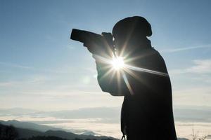 silhouette de jeune photographe tenant un appareil photo avec paysage de montagne