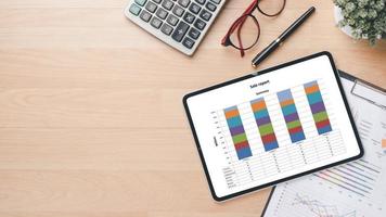 tablette avec graphiques et rapports sur le lieu de travail de bureau. vue de dessus mise à plat photo