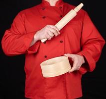 cuisinier dans une rouge uniforme en portant une en bois roulant épingle et rond tamis photo