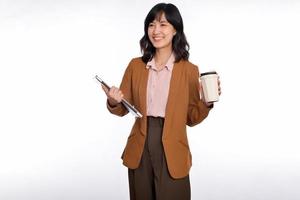 magnifique souriant Jeune asiatique femme d'affaires porter portable ordinateur et tasse de café à aller tandis que permanent isolé plus de blanc Contexte photo