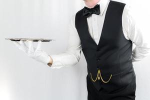 portrait de serveur ou majordome dans blanc gants en portant argent plateau sur blanc Contexte. concept de un service industrie et professionnel hospitalité. photo
