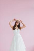 Jeune la mariée dans blanc robe avec fleur couronne sur sa tête posant dans le studio photo
