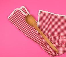 en bois cuillère sur une rouge cuisine serviette, rose Contexte photo