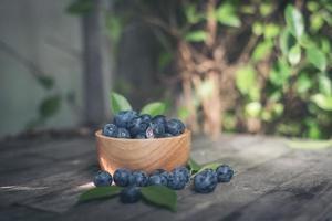 Prunes fraîches dans un bol en bois sur fond de bois ancien photo